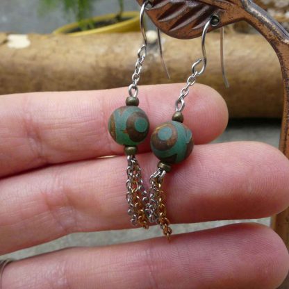 slinger oorbellen met metalen kwastje en groene steen met bruine ogen