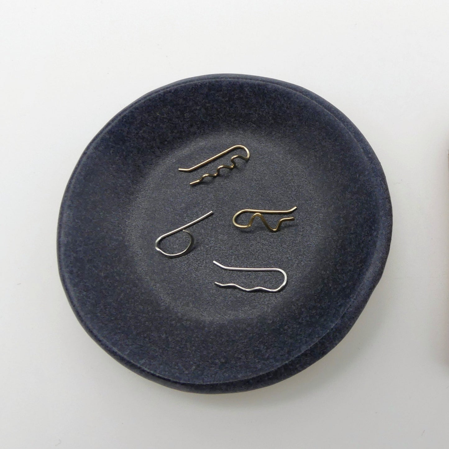 blauw aardewerk schaaltje met 4 losse oorbellen in verschillende handgemaakte vormen