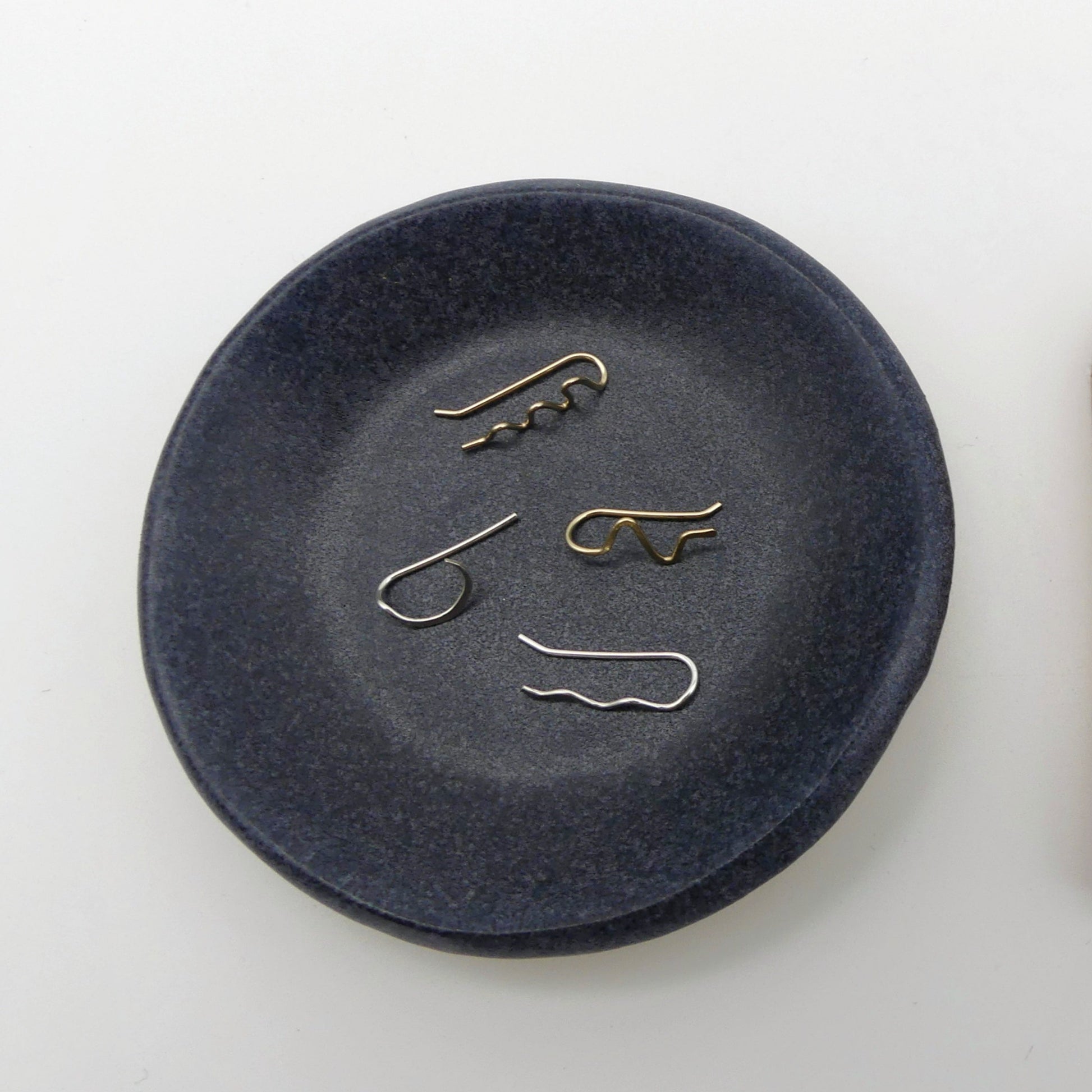 blauw aardewerk schaaltje met 4 losse oorbellen in verschillende handgemaakte vormen