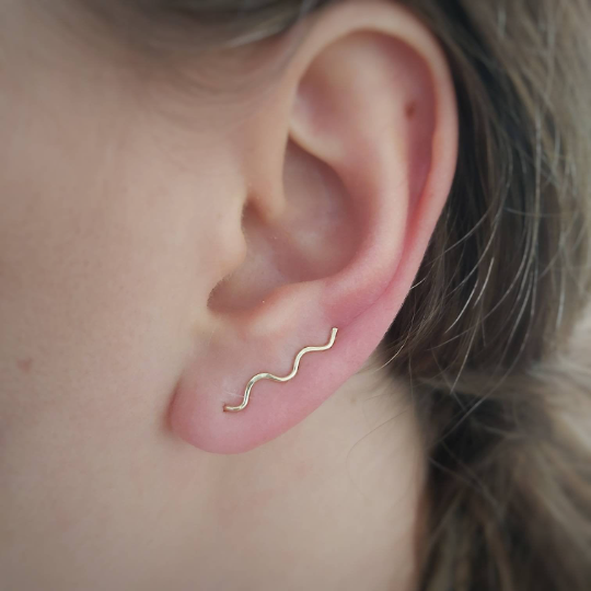 oor met gouden horizontale oorbel in organisch golvende vorm