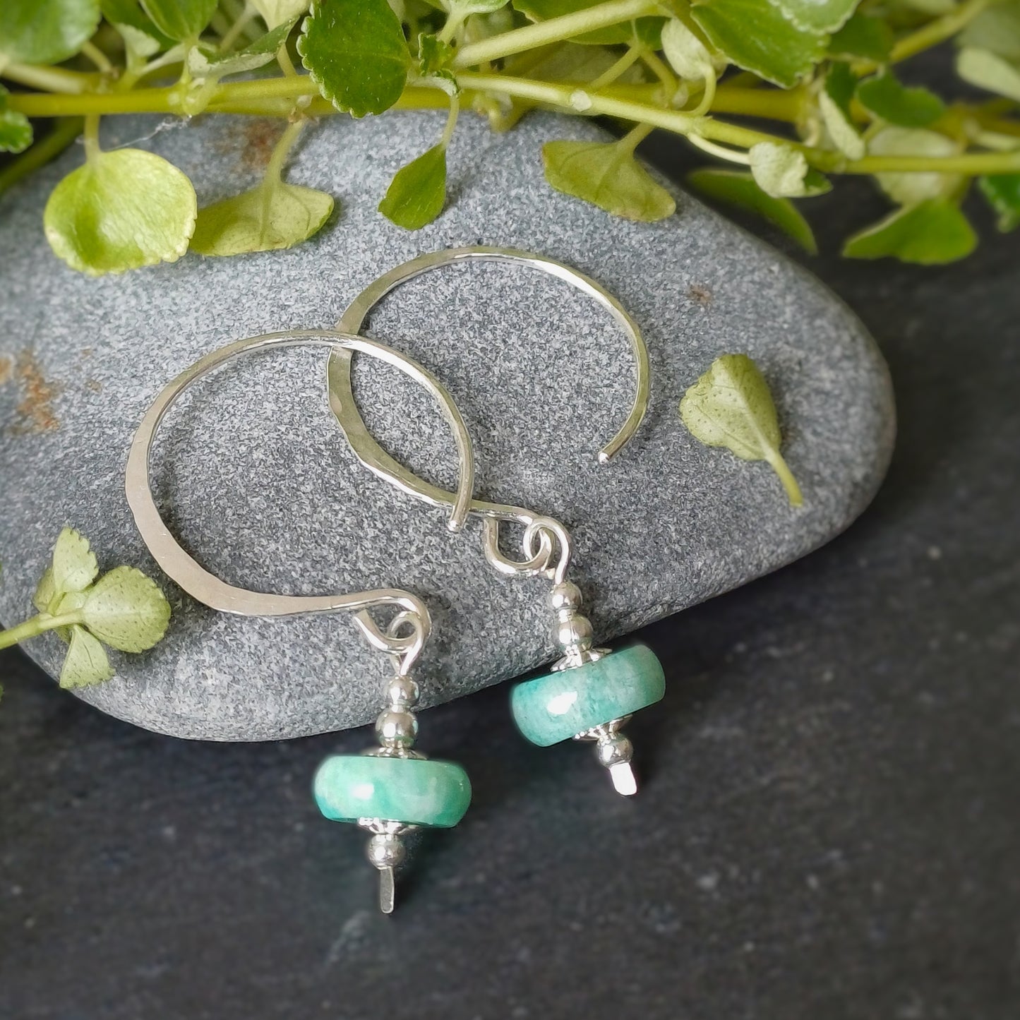 grote zilveren oorbellen met blauwe amazoniet rondelle en flower cap afwerking op steen 