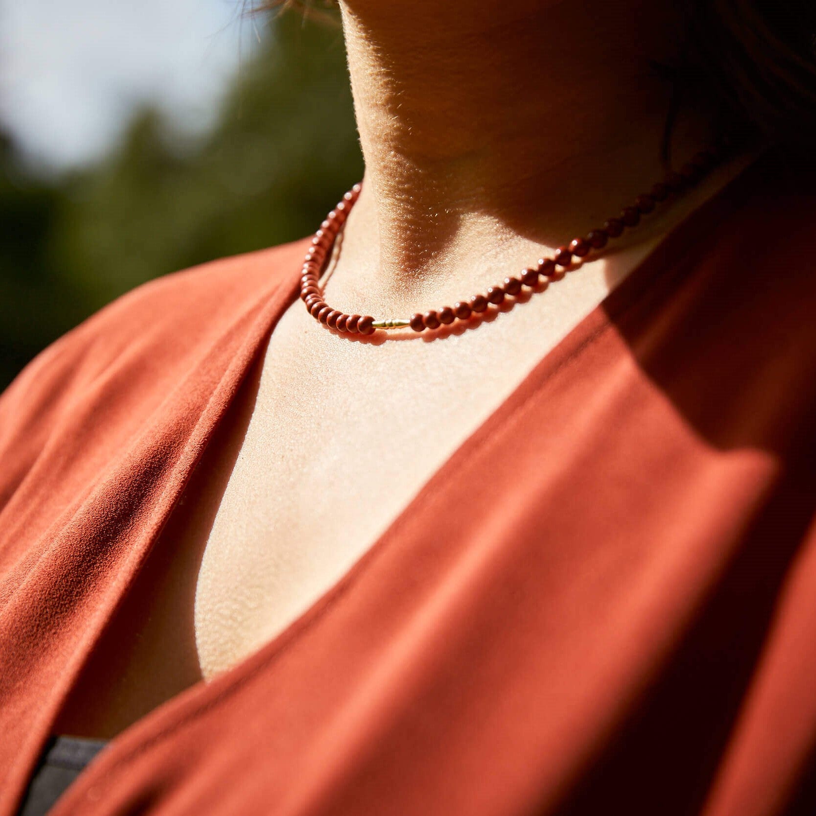 vrouw met rode blouse en bijpassende ketting van natuursteen 